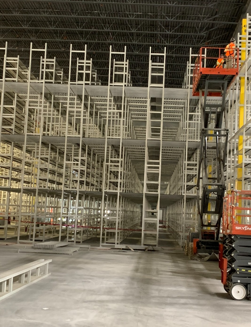 Installers on a lift building a large multi-level shelving pick tower