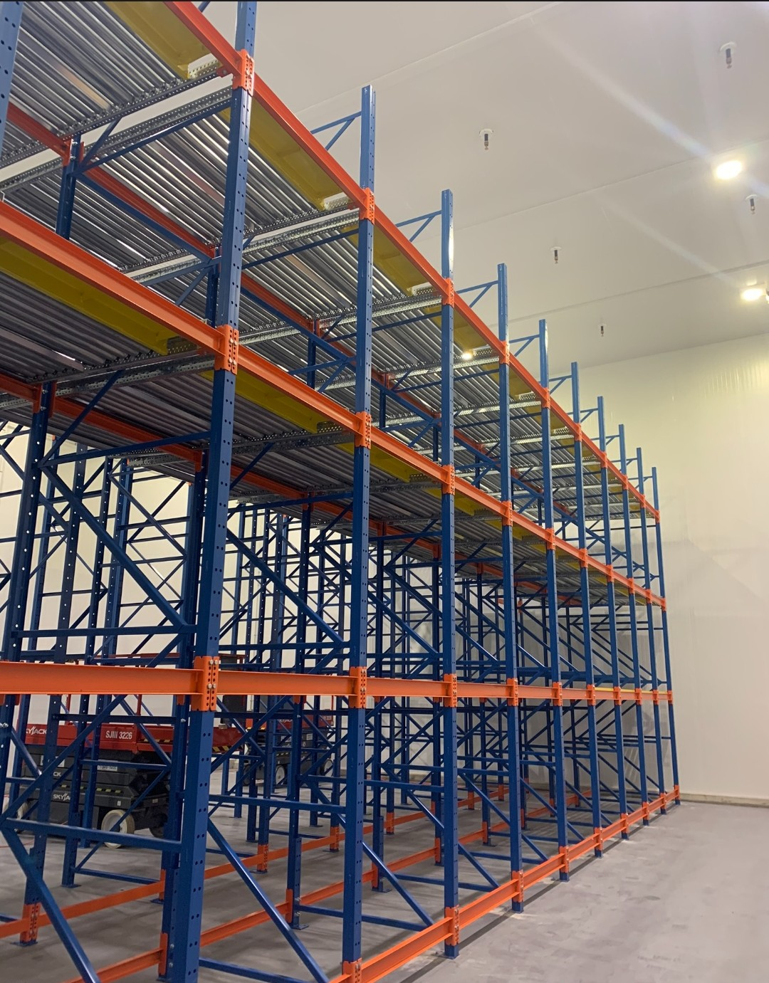 Multi-level pallet flow racking with orange beams and blue uprights